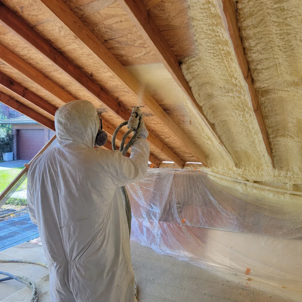 Contractor applying professional spray foam insulation to a residential roof